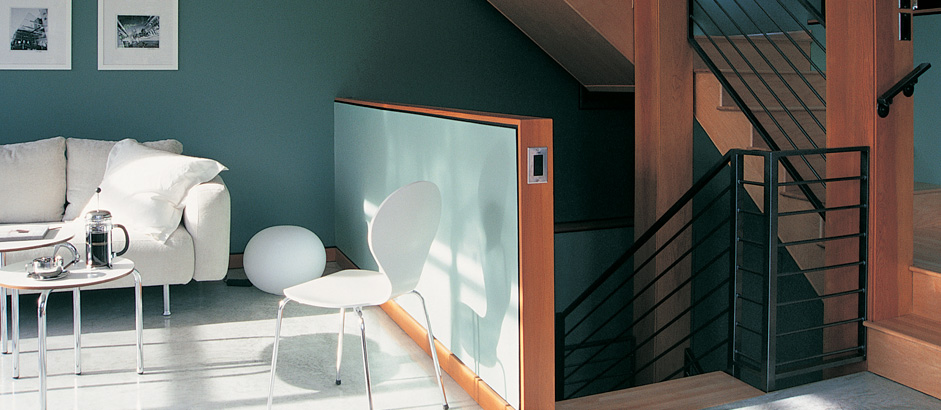 A bright living room with a teal feature wall and a white armchair