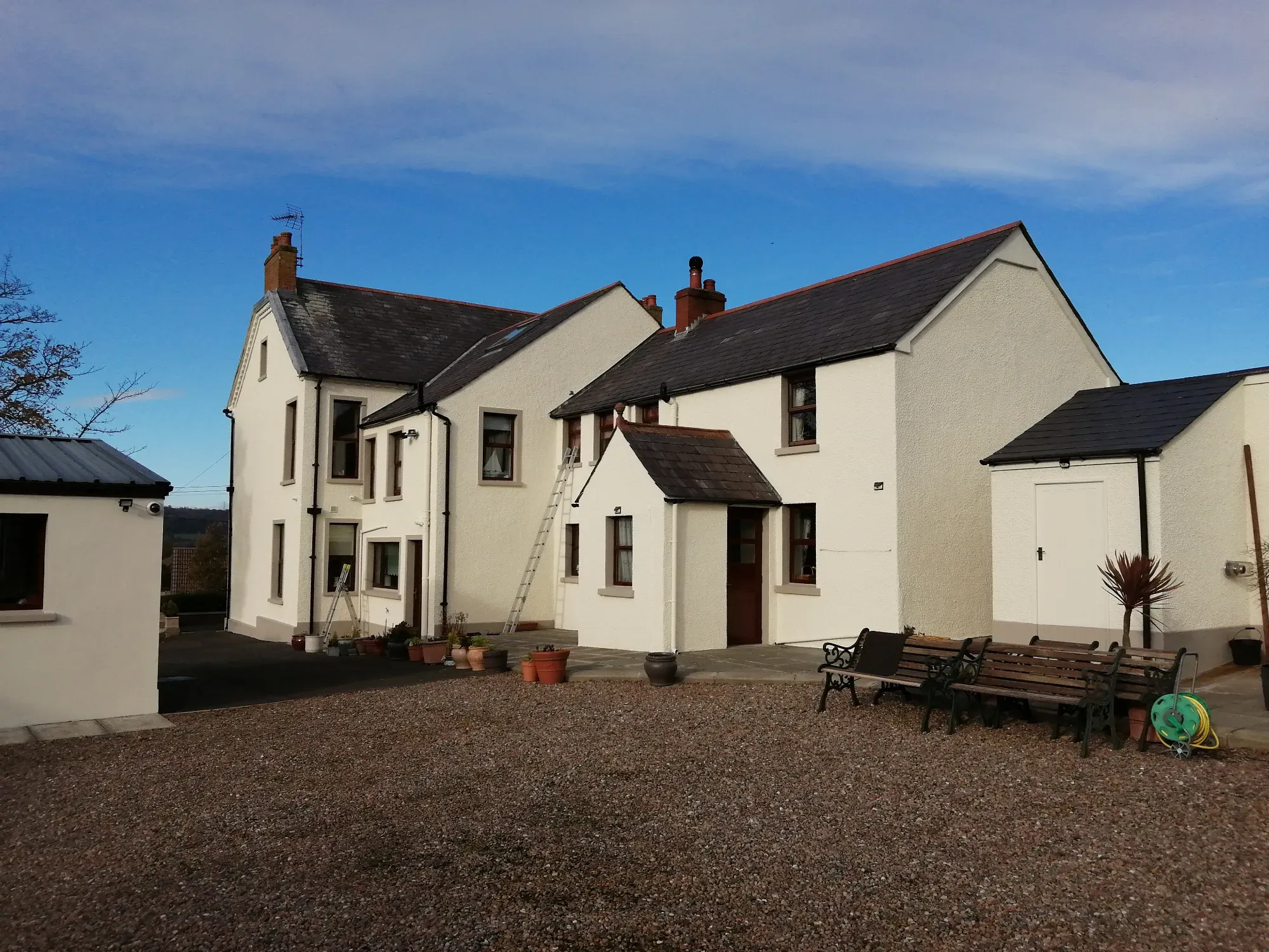 A large white farmhouse freshly painted, with a blue sky behind