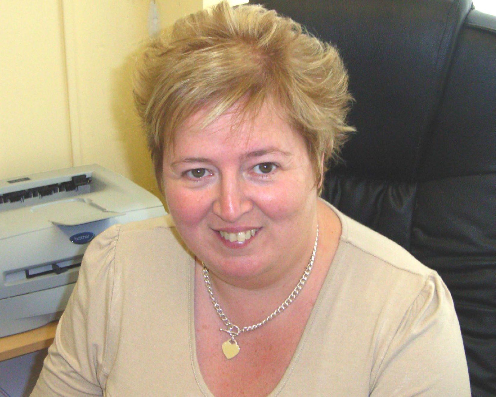 Jayne Sives smiling at her desk